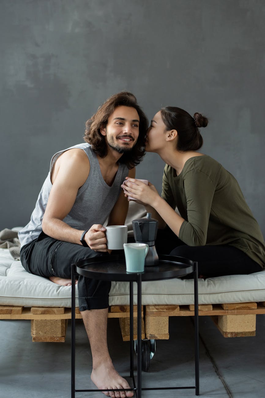 woman in green top whispering to a man in a gray tank top